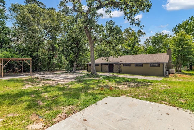 10650 Forest Creek Dr, Conroe, TX 77318 - rear view of property featuring a lawn, a chimney, a patio, a carport, and view of wooded area
