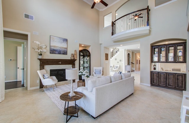 5719 Avon Landing Ln, Sugar Land, TX 77479 - living area with a ceiling fan, a high ceiling, a high end fireplace, stairway, and crown molding