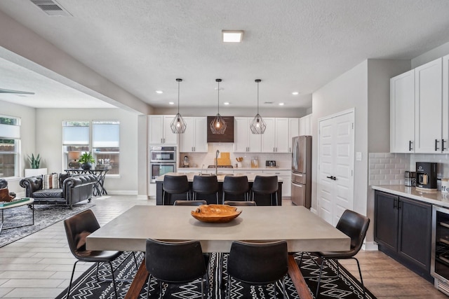 6019 Rivergrove Bend Dr, Humble, TX 77346 - dining area with recessed lighting, light wood-style flooring, a textured ceiling, and beverage cooler