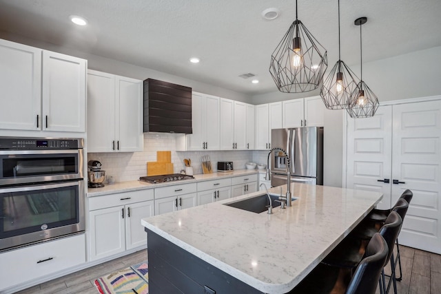 6019 Rivergrove Bend Dr, Humble, TX 77346 - kitchen with appliances with stainless steel finishes, light wood-style flooring, premium range hood, backsplash, and light stone countertops