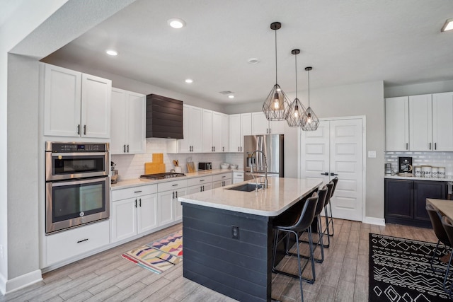 6019 Rivergrove Bend Dr, Humble, TX 77346 - kitchen with stainless steel appliances, light wood-style flooring, light countertops, decorative backsplash, and a breakfast bar area