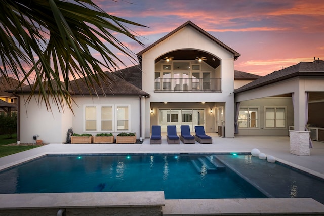 3971 Rolling Thicket Dr, Spring, TX 77386 - back of property at dusk featuring a balcony, stucco siding, a patio area, and an outdoor pool