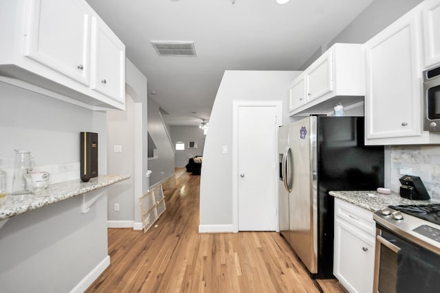 8710 Beverlyhill St Unit 201, Houston, TX 77063 - kitchen featuring white cabinetry, light wood-style floors, appliances with stainless steel finishes, light stone counters, and decorative backsplash