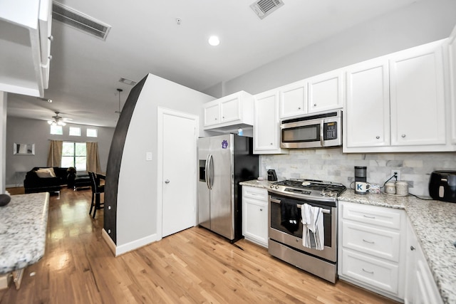 8710 Beverlyhill St Unit 201, Houston, TX 77063 - kitchen featuring appliances with stainless steel finishes, tasteful backsplash, white cabinets, and light wood-style flooring