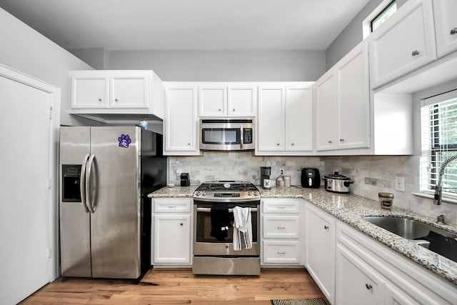 8710 Beverlyhill St Unit 201, Houston, TX 77063 - kitchen featuring stainless steel appliances, light wood-style floors, white cabinets, and decorative backsplash