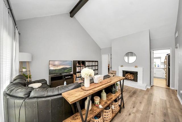 2100 Tanglewilde St Unit 312, Houston, TX 77063 - living room featuring light wood-style floors, beam ceiling, a brick fireplace, and high vaulted ceiling