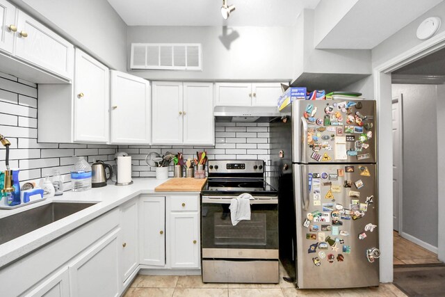 2100 Tanglewilde St Unit 312, Houston, TX 77063 - kitchen featuring stainless steel appliances, under cabinet range hood, tasteful backsplash, and white cabinets