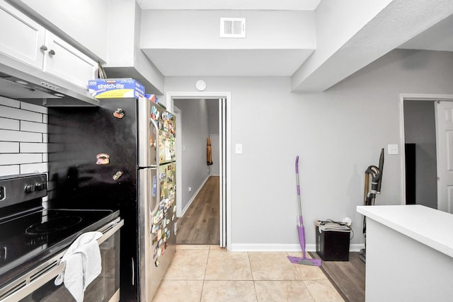 2100 Tanglewilde St Unit 312, Houston, TX 77063 - kitchen featuring stainless steel range with electric cooktop, white cabinets, light tile patterned floors, light countertops, and extractor fan