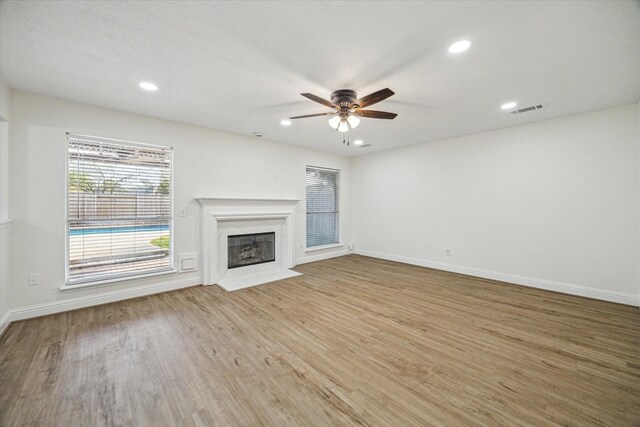18035 Berry Branch Dr, Houston, TX 77084 - unfurnished living room with light wood finished floors, a ceiling fan, a fireplace with flush hearth, and recessed lighting