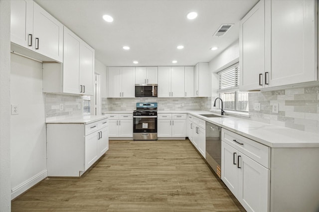 18035 Berry Branch Dr, Houston, TX 77084 - kitchen featuring stainless steel appliances, light wood finished floors, backsplash, recessed lighting, and white cabinets