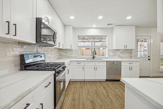 18035 Berry Branch Dr, Houston, TX 77084 - kitchen featuring appliances with stainless steel finishes, light wood-style floors, backsplash, white cabinetry, and light stone countertops