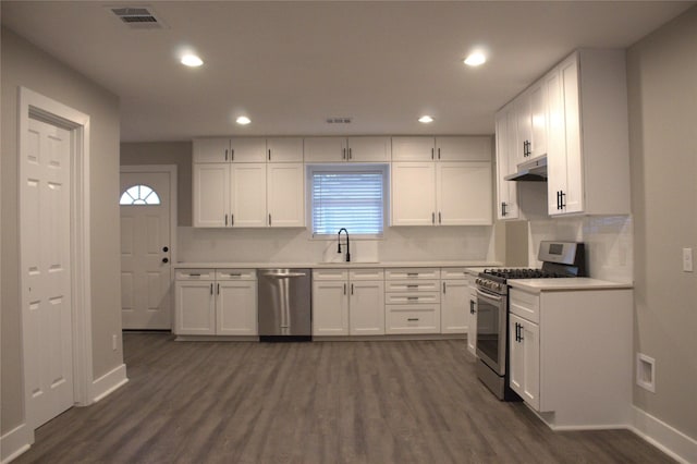 5105 Oak Ave, Pasadena, TX 77503 - kitchen with stainless steel appliances, under cabinet range hood, dark wood-type flooring, light countertops, and white cabinetry
