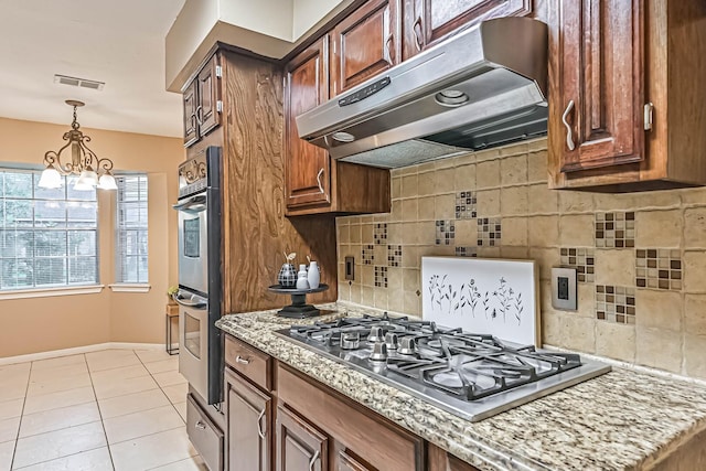 55 Sweetgum Ct, Lake Jackson, TX 77566 - kitchen featuring under cabinet range hood, appliances with stainless steel finishes, backsplash, light stone countertops, and light tile patterned floors