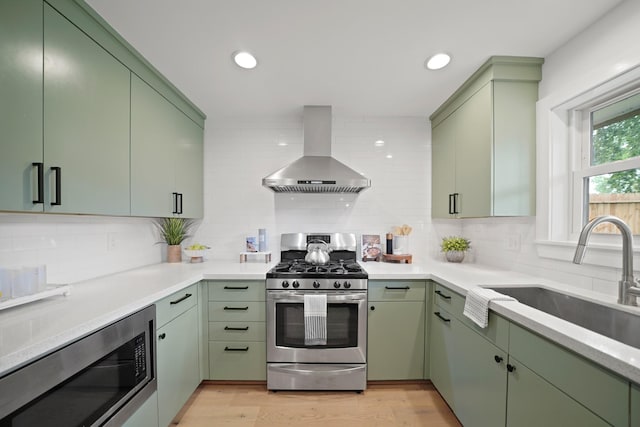5730 Chrystell Ln, Houston, TX 77092 - kitchen with wall chimney range hood, stainless steel appliances, green cabinetry, and recessed lighting