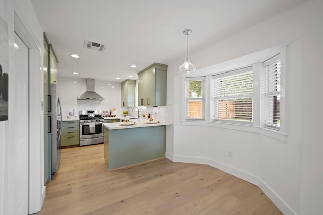 5730 Chrystell Ln, Houston, TX 77092 - kitchen featuring appliances with stainless steel finishes, wall chimney exhaust hood, a peninsula, light wood finished floors, and recessed lighting