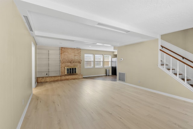 3315 Crestdale Dr, Houston, TX 77080 - unfurnished living room with light wood-style floors, built in shelves, a brick fireplace, and stairway