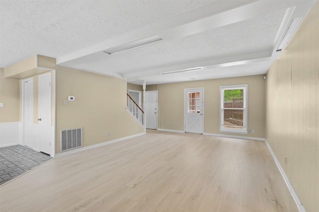 3315 Crestdale Dr, Houston, TX 77080 - unfurnished living room with a textured ceiling, light wood-type flooring, and stairs
