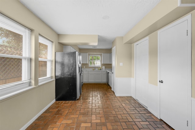 3315 Crestdale Dr, Houston, TX 77080 - kitchen with fridge with ice dispenser, brick flooring, a wainscoted wall, light countertops, and white cabinetry