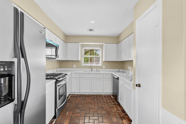 3315 Crestdale Dr, Houston, TX 77080 - kitchen with stainless steel appliances, brick floors, white cabinets, and light stone countertops