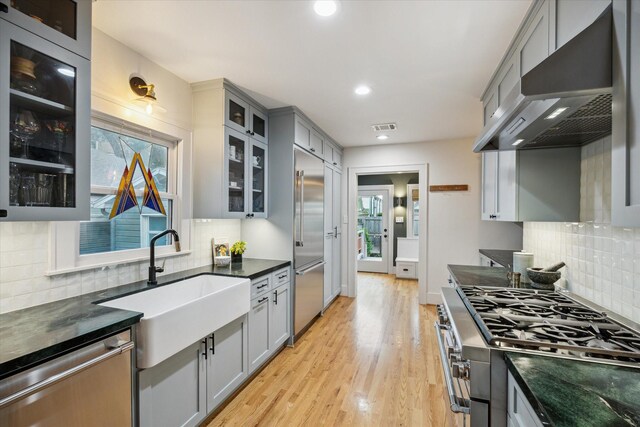 711 Pizer St, Houston, TX 77009 - kitchen with range hood, stainless steel appliances, gray cabinetry, tasteful backsplash, and light wood-style floors