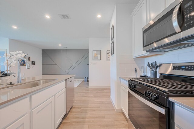 903 Curly Angora Ct, Rosharon, TX 77583 - kitchen featuring appliances with stainless steel finishes, light wood-style flooring, recessed lighting, tasteful backsplash, and white cabinetry