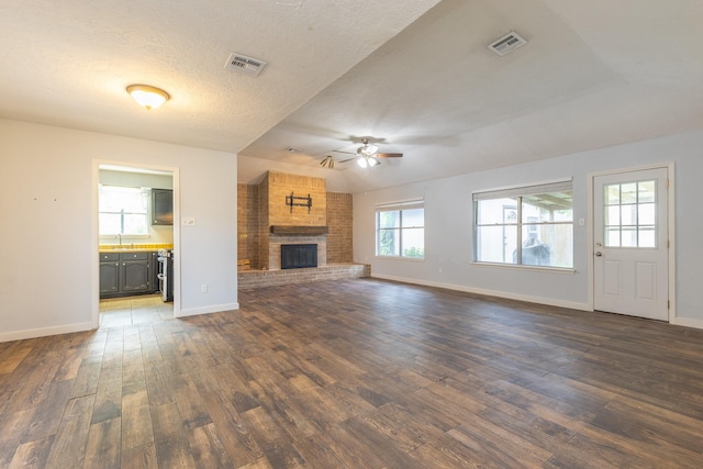 9938 Rustic Rock Rd, La Porte, TX 77571 - unfurnished living room with a ceiling fan, dark wood finished floors, a fireplace, and a textured ceiling