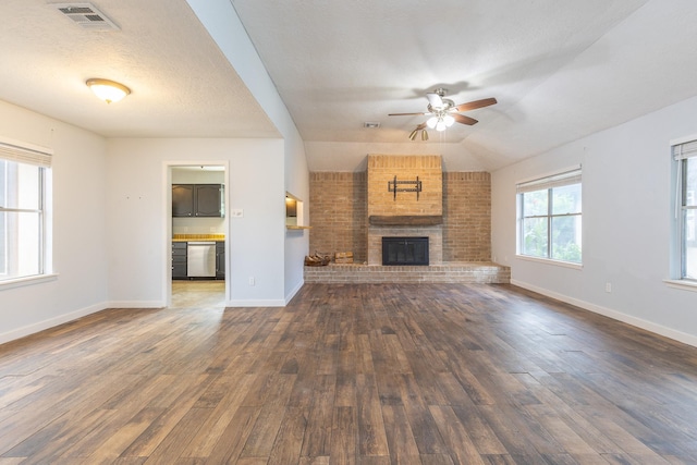 9938 Rustic Rock Rd, La Porte, TX 77571 - unfurnished living room with ceiling fan, wood-type flooring, a brick fireplace, and a textured ceiling