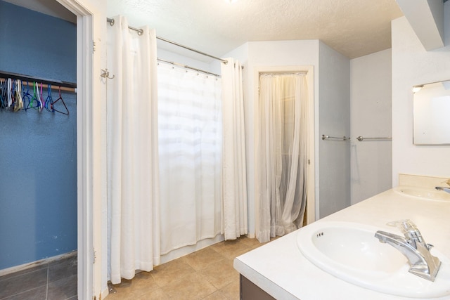 9938 Rustic Rock Rd, La Porte, TX 77571 - bathroom featuring double vanity, tile patterned flooring, curtained shower, and a textured ceiling