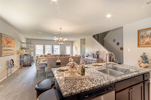 1614 Chase Anchor Ct, Richmond, TX 77469 - kitchen featuring stainless steel dishwasher, open floor plan, light wood-style flooring, a chandelier, and a kitchen island with sink