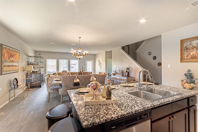 1614 Chase Anchor Ct, Richmond, TX 77469 - kitchen featuring stainless steel dishwasher, open floor plan, light wood-style flooring, a chandelier, and a kitchen island with sink