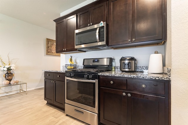 1614 Chase Anchor Ct, Richmond, TX 77469 - kitchen with appliances with stainless steel finishes, dark stone countertops, light wood finished floors, and dark brown cabinets