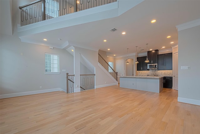8324 Ginger Oak St, Houston, TX 77055 - kitchen with stainless steel microwave, light countertops, open floor plan, backsplash, and a center island with sink