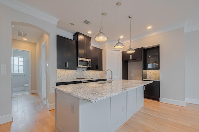 8324 Ginger Oak St, Houston, TX 77055 - kitchen featuring appliances with stainless steel finishes, arched walkways, decorative backsplash, light wood-style floors, and light stone countertops