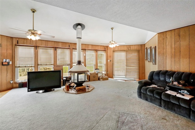 174 Sand Shoals Rd, Freeport, TX 77541 - living area with a ceiling fan, wooden walls, a wood stove, plenty of natural light, and carpet flooring