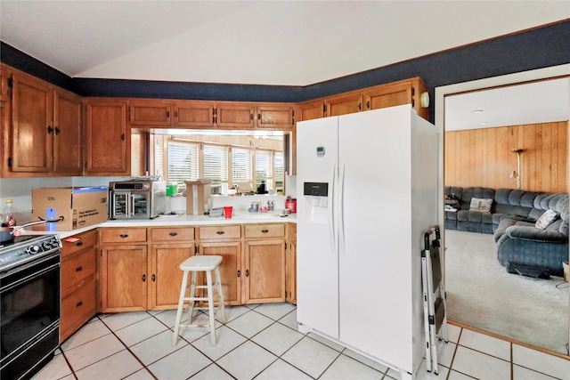 174 Sand Shoals Rd, Freeport, TX 77541 - kitchen with white fridge with ice dispenser, black range with electric stovetop, lofted ceiling, light countertops, and light tile patterned floors