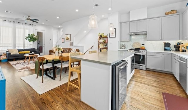 2753 Clinton Dr, Houston, TX 77020 - kitchen with stainless steel gas range, wine cooler, open floor plan, under cabinet range hood, and light countertops