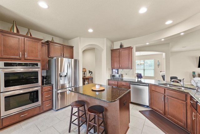 24506 Rossmore Hill Ct, Spring, TX 77389 - kitchen featuring appliances with stainless steel finishes, arched walkways, a kitchen island, dark stone countertops, and a breakfast bar area