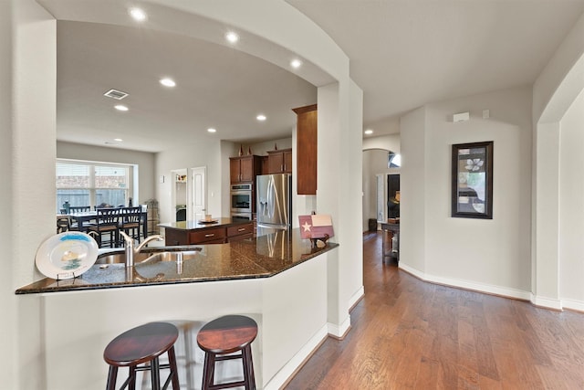 24506 Rossmore Hill Ct, Spring, TX 77389 - kitchen featuring appliances with stainless steel finishes, a kitchen island, dark wood-style floors, arched walkways, and recessed lighting