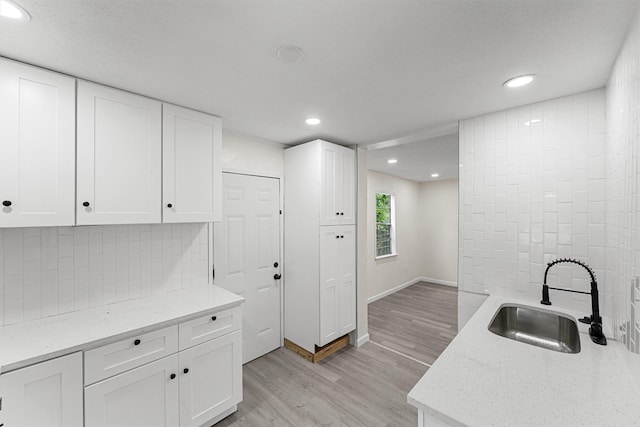 4715 Engleford St, Houston, TX 77026 - kitchen featuring light wood-type flooring, recessed lighting, backsplash, white cabinets, and light stone counters