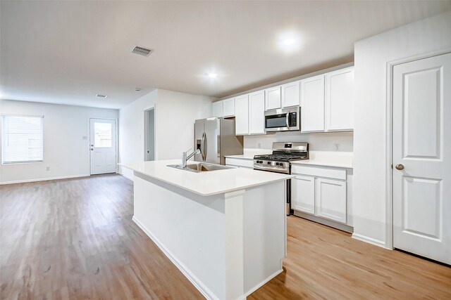 9603 Fulvetta Briar Ct, Baytown, TX 77521 - kitchen with appliances with stainless steel finishes, light wood-type flooring, an island with sink, white cabinetry, and recessed lighting