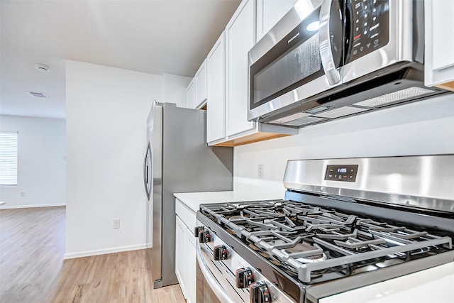 9603 Fulvetta Briar Ct, Baytown, TX 77521 - kitchen with stainless steel appliances, white cabinetry, light wood-type flooring, and light countertops