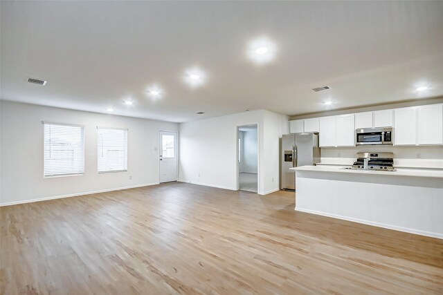 9603 Fulvetta Briar Ct, Baytown, TX 77521 - kitchen featuring stainless steel appliances, white cabinetry, open floor plan, light wood-type flooring, and recessed lighting