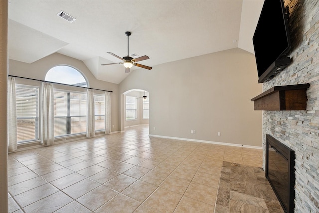 2219 Fenton Rock Ln, Katy, TX 77494 - unfurnished living room with a stone fireplace, ceiling fan, vaulted ceiling, light tile patterned flooring, and arched walkways