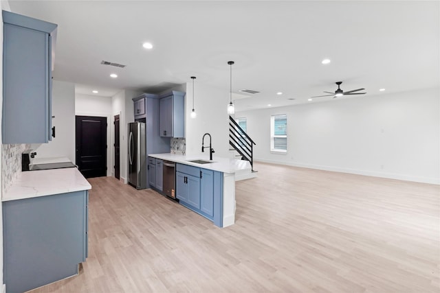 8136 Chateau St, Houston, TX 77028 - kitchen with appliances with stainless steel finishes, a peninsula, light wood-style flooring, tasteful backsplash, and a ceiling fan