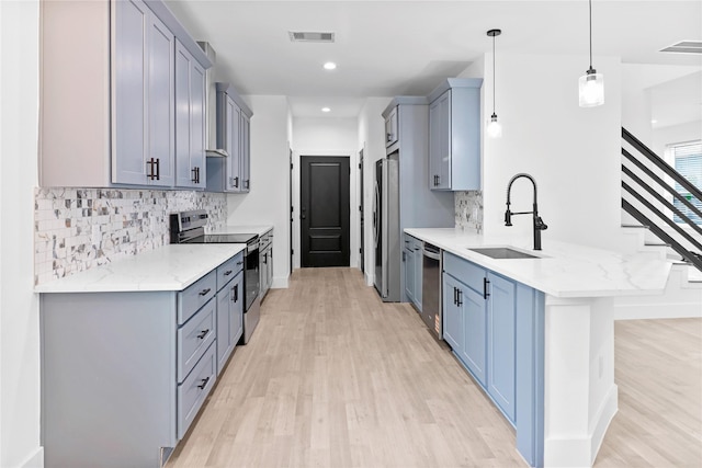 8136 Chateau St, Houston, TX 77028 - kitchen with appliances with stainless steel finishes, a peninsula, light wood-style floors, tasteful backsplash, and light stone counters