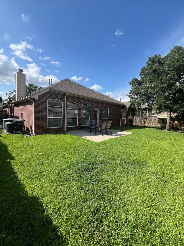 6315 Oakmont Creek Dr, Spring, TX 77379 - rear view of property featuring a patio, a lawn, brick siding, and a chimney