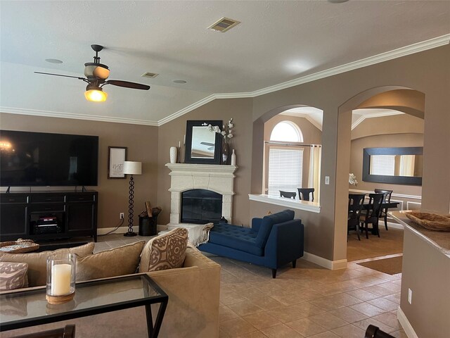 6315 Oakmont Creek Dr, Spring, TX 77379 - living room with a glass covered fireplace, a ceiling fan, light tile patterned floors, arched walkways, and crown molding