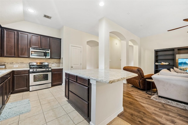 12747 Bridle Springs Ln, Houston, TX 77044 - kitchen featuring appliances with stainless steel finishes, open floor plan, dark brown cabinetry, decorative backsplash, and a ceiling fan