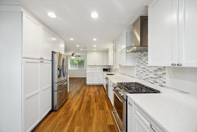 5707 Darnell St, Houston, TX 77096 - kitchen with appliances with stainless steel finishes, wall chimney range hood, wood finished floors, white cabinetry, and decorative backsplash