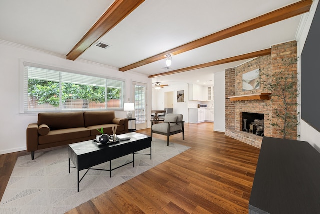 5707 Darnell St, Houston, TX 77096 - living room featuring wood finished floors, beam ceiling, a brick fireplace, ceiling fan, and ornamental molding